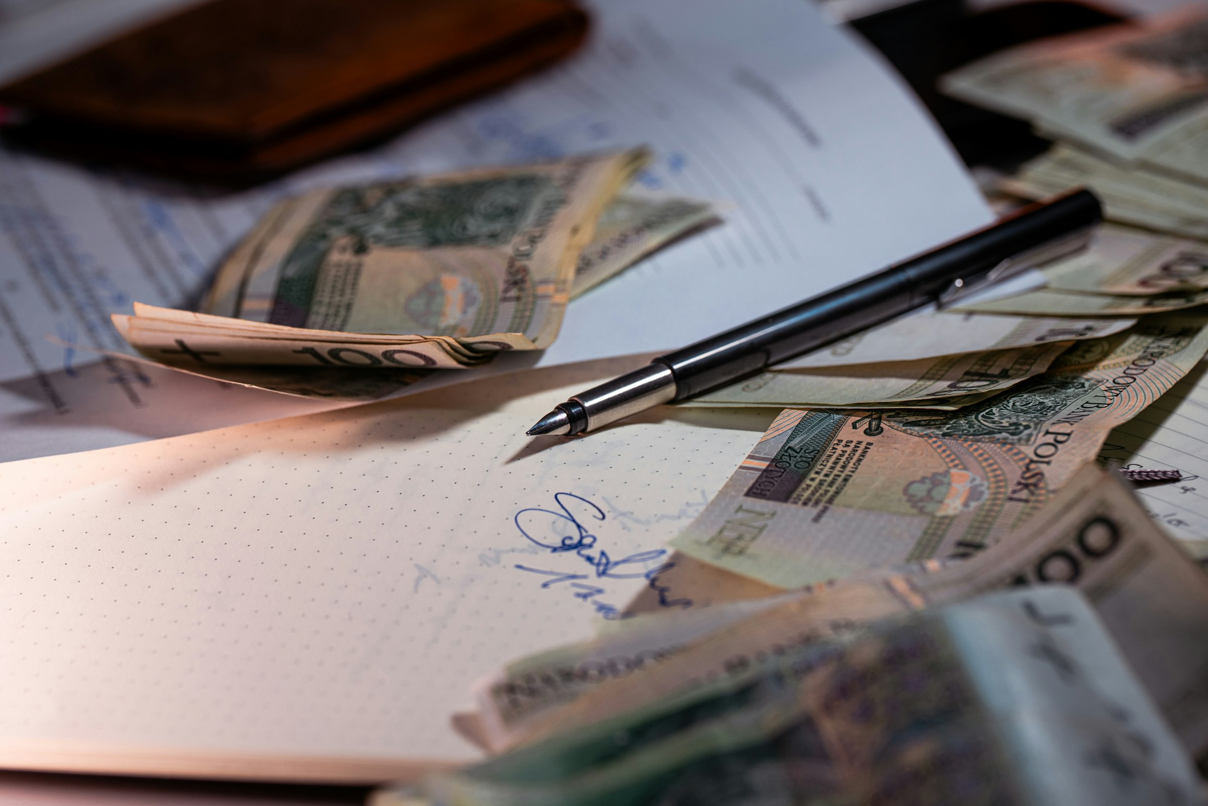 Pióro i banknoty na dokumentach księgowych